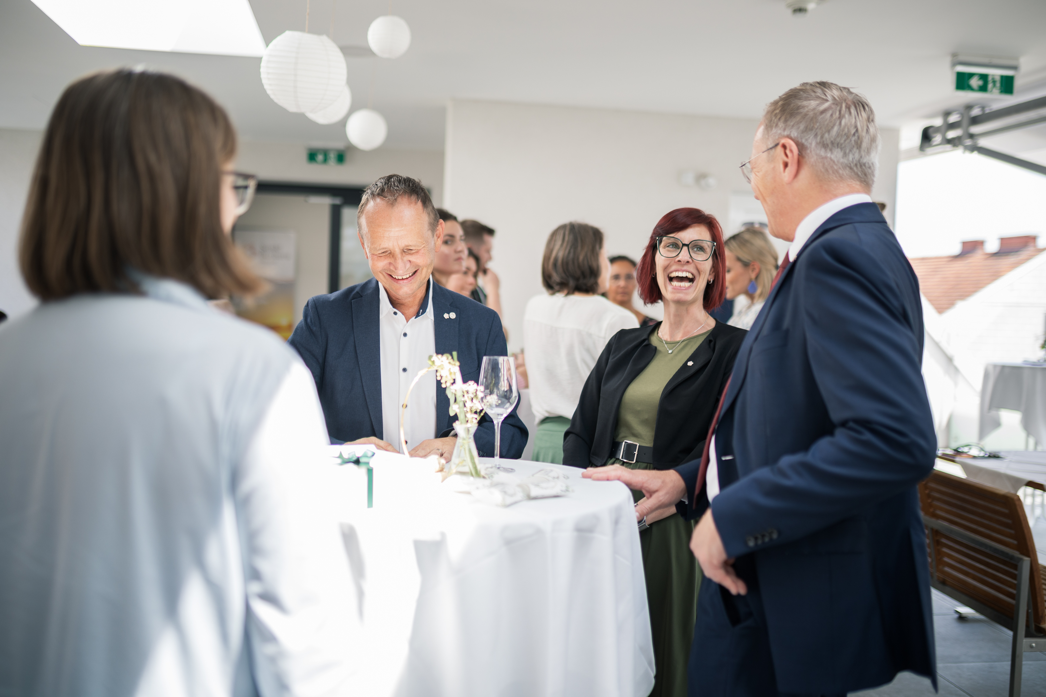 Landeshauptmann im Gespräch / Land OOE Der Landeshauptmann spricht an einem runden Stehtisch mit einem Mann und einer Frau.