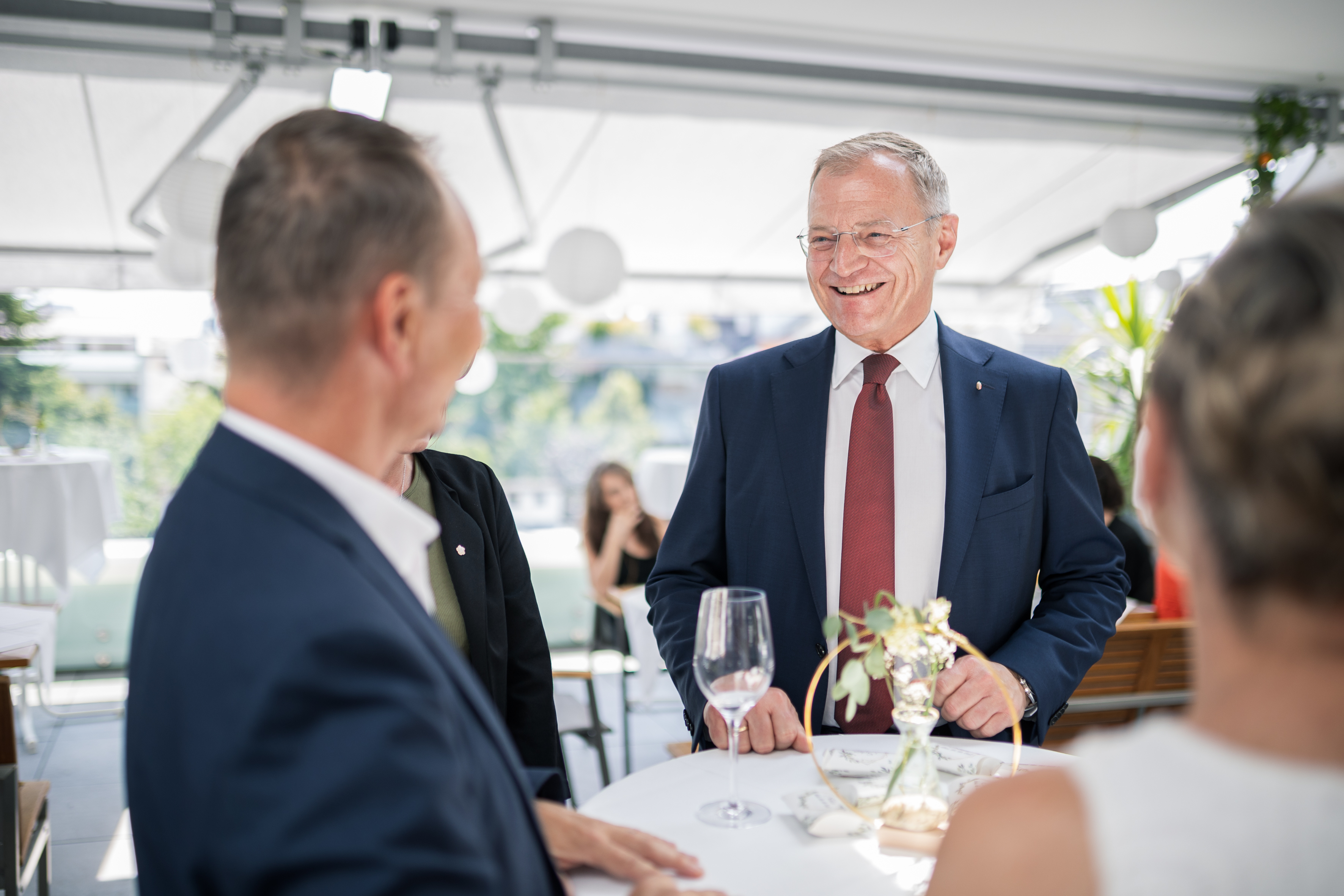 Landeshauptmann im Gespräch / Land OOE Der Landeshauptmann lacht an einem runden Stehtisch gemeinsam mit den anwesenden Personen.